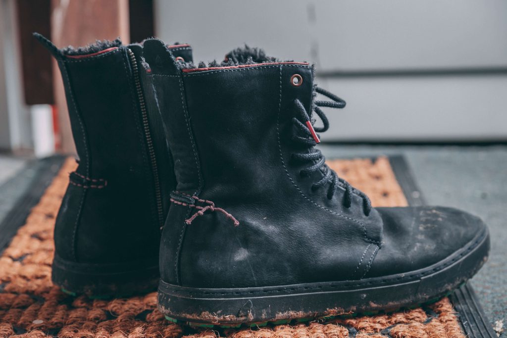 Workwear and corporate gifts - pair of black workboots on a doormat inside
